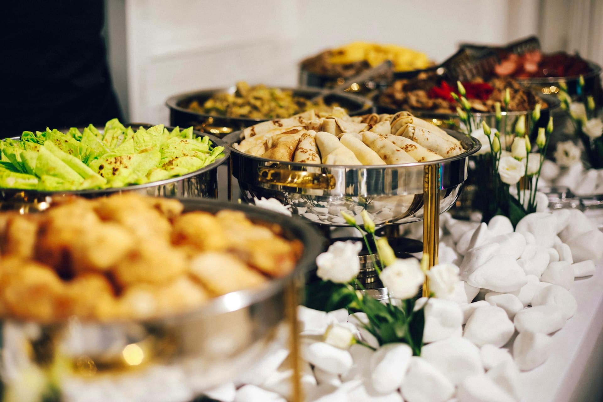 Elegant catering buffet setup with silver chafing dishes and floral arrangements